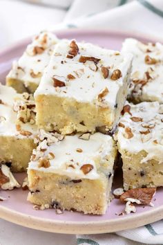 several pieces of cake on a plate with white frosting and pecans in the middle