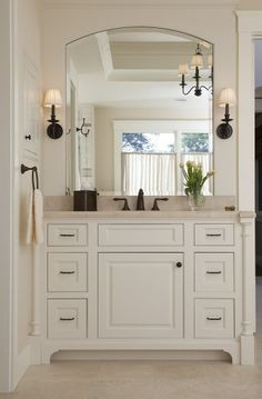 a white bathroom with double sinks and large mirror above it's countertop, along with an open doorway leading to another room