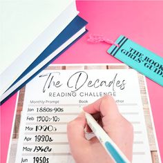 a person writing on a book with a pen and paper clip next to it that reads the decades reading challenge