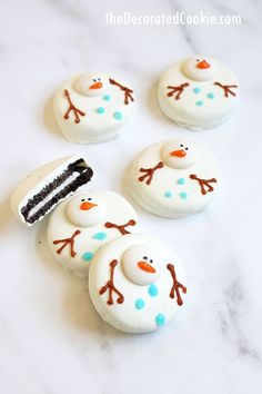 four frosted snowman cookies sitting on top of a white counter