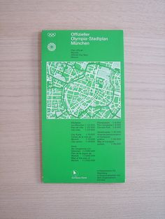 a green book with white writing on it and a map in the middle, sitting on top of a gray surface