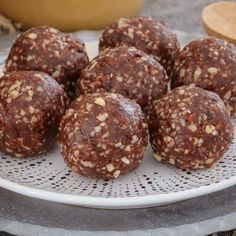 several chocolate balls on a white plate next to a wooden spoon