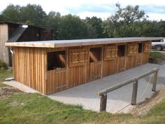 a large wooden building sitting on top of a lush green field next to a forest