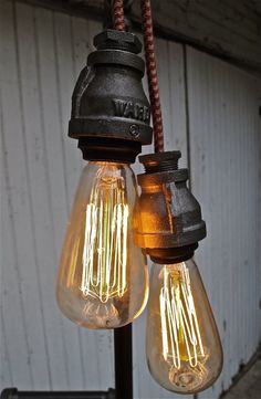 two light bulbs are hanging from a pole