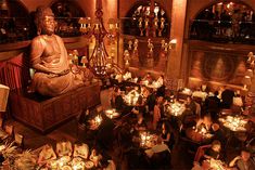 a group of people sitting around a buddha statue in a room filled with lit candles