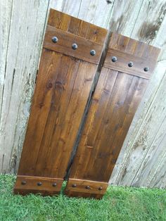 two wooden doors sitting in the grass next to a wood fence with metal rivets