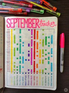 an open planner with markers and pens on it, next to a notebook that says september trackerr