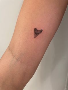 a small black heart tattoo on the arm