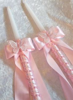 two pink candles with bows on them