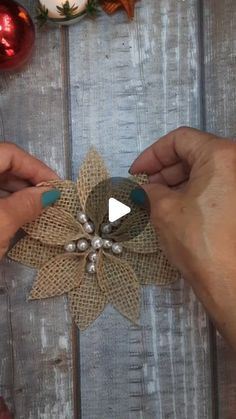 two hands are working on an ornament with burlap and pearls in it