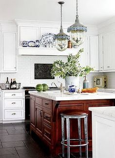 a kitchen with white cabinets and an island in front of the stove top is filled with dishes