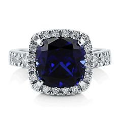 a cushion cut blue sapphire and diamond ring with halos around the band, set in 18k white gold