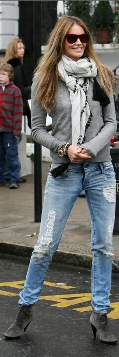 a woman standing on the street with her hand in her pocket and wearing ripped jeans