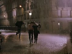 two people walking down the street in the rain with umbrellas over their heads,