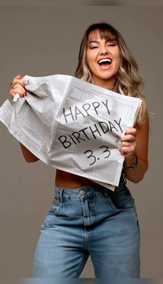 a woman holding up a newspaper with the words happy birthday on it