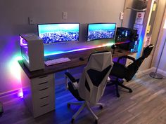 two computer monitors sitting next to each other on top of a wooden desk in an office