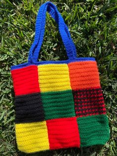 a multicolored crocheted bag sitting in the grass