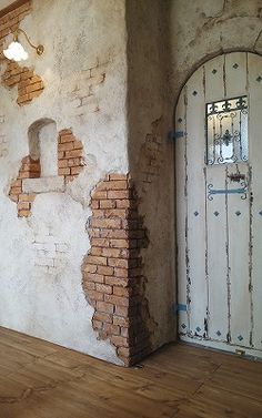 an empty room with a door and brick wall in the corner, surrounded by wood flooring