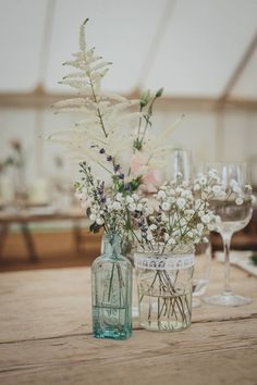 two vases filled with flowers sitting on top of a table next to wine glasses