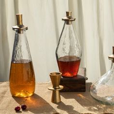 three vases sitting on top of a table next to each other with liquid in them