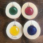 four wooden buttons with different colors on them sitting on top of a wood table next to each other