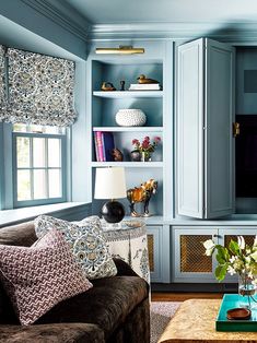 a living room with blue walls and furniture in the corner, along with bookshelves