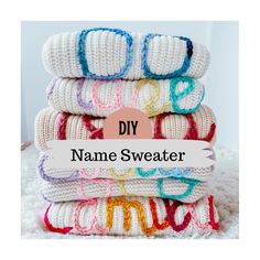 a stack of white knitted blankets with the words diy name sweater on top