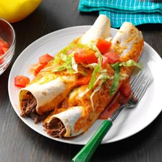 a white plate topped with burritos covered in meat and veggies