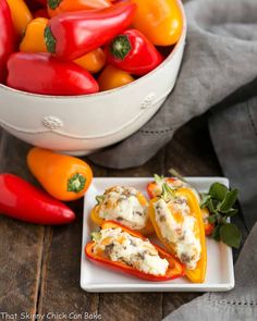 stuffed bell peppers on a white plate next to some red and yellow peppers in a bowl