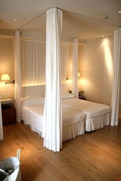 a white canopy bed sitting inside of a bedroom