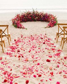 the aisle is decorated with pink flowers and white candles for an outdoor ceremony on the beach