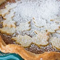 an uncooked pie with powdered sugar on top sits on a blue plate