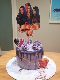 a purple cake with two pictures on top and decorations around the edges, sitting on a table in front of a wall