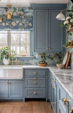 a kitchen with blue cabinets and floral wallpaper on the walls, gold faucets