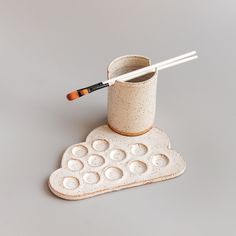 a cup with chopsticks in it sitting on top of a coaster that has circles and dots