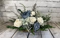 a vase filled with blue and white flowers on top of a wooden table next to a brick wall