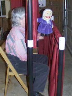 an old man sitting in a chair with a puppet on the back of his head