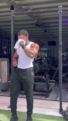 a man in white shirt and black pants standing next to a gym area with equipment