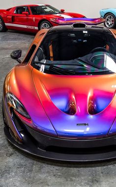 three different colored sports cars parked in a garage