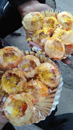 two people holding up small pastries with different toppings on them in their hands