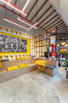 the interior of a modern office building with yellow benches and art on the wall behind it