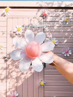 a person holding a balloon in front of a pink wall with white flowers on it