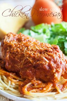 chicken parmesan on top of spaghetti with lettuce and tomatoes in the background