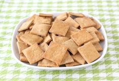 a white bowl filled with crackers on top of a green and white checkered table cloth