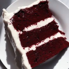 a piece of red velvet cake with white frosting on a plate, ready to be eaten