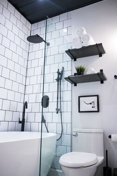 a white toilet sitting next to a bath tub under a bathroom mirror with shelves above it