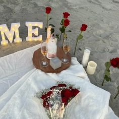 the table is set up with flowers and wine glasses for an intimate dinner on the beach