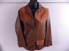 "Beautiful vintage leather jacket, in two-tone buckskin. Soft and supple tanned leather body with contrasting suede panels on the shoulders and pocket flaps. Fully lined in silky rayon. Two front buttons and two at each cuff. Very cute Western-style jacket, which would be perfect with jeans or a skirt. Jacket and lining are in excellent condition- very lightly worn. A tiny area of scratching on right shoulder- visible in last photo, but really minimal. Leather is amazingly soft and buttery- no stiffness or dry rot at all! Measurements: Bust: 33-34\" (marked 34) Waist: 32\" Sleeve length: 23\" Overall length (collar to hem): 28\"" Brown Leather Jacket With Suede Overlays, Fitted Brown Blazer With Snap Buttons, Western Leather Outerwear With Snap Buttons, Classic Brown Outerwear With Suede Overlays, Western Brown Fitted Leather Jacket, Western Brown Outerwear For Work, Western Style Leather Jacket For Workwear In Winter, Fitted Leather Jacket With Suede Overlays, Fitted Brown Outerwear With Suede Overlays