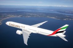 an emirates airplane flying over the ocean