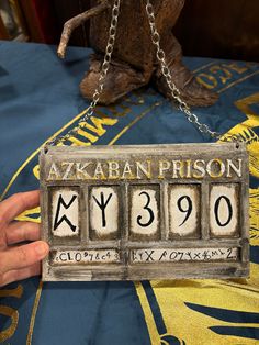 a person holding up a metal sign with numbers on it that reads azkaban prison